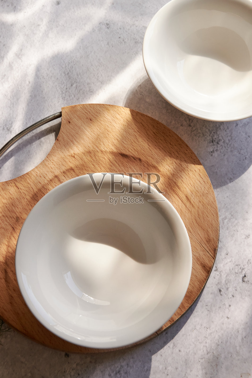 在洒满阳光的桌子上，把白色的碗倒在水泥地上照片摄影图片