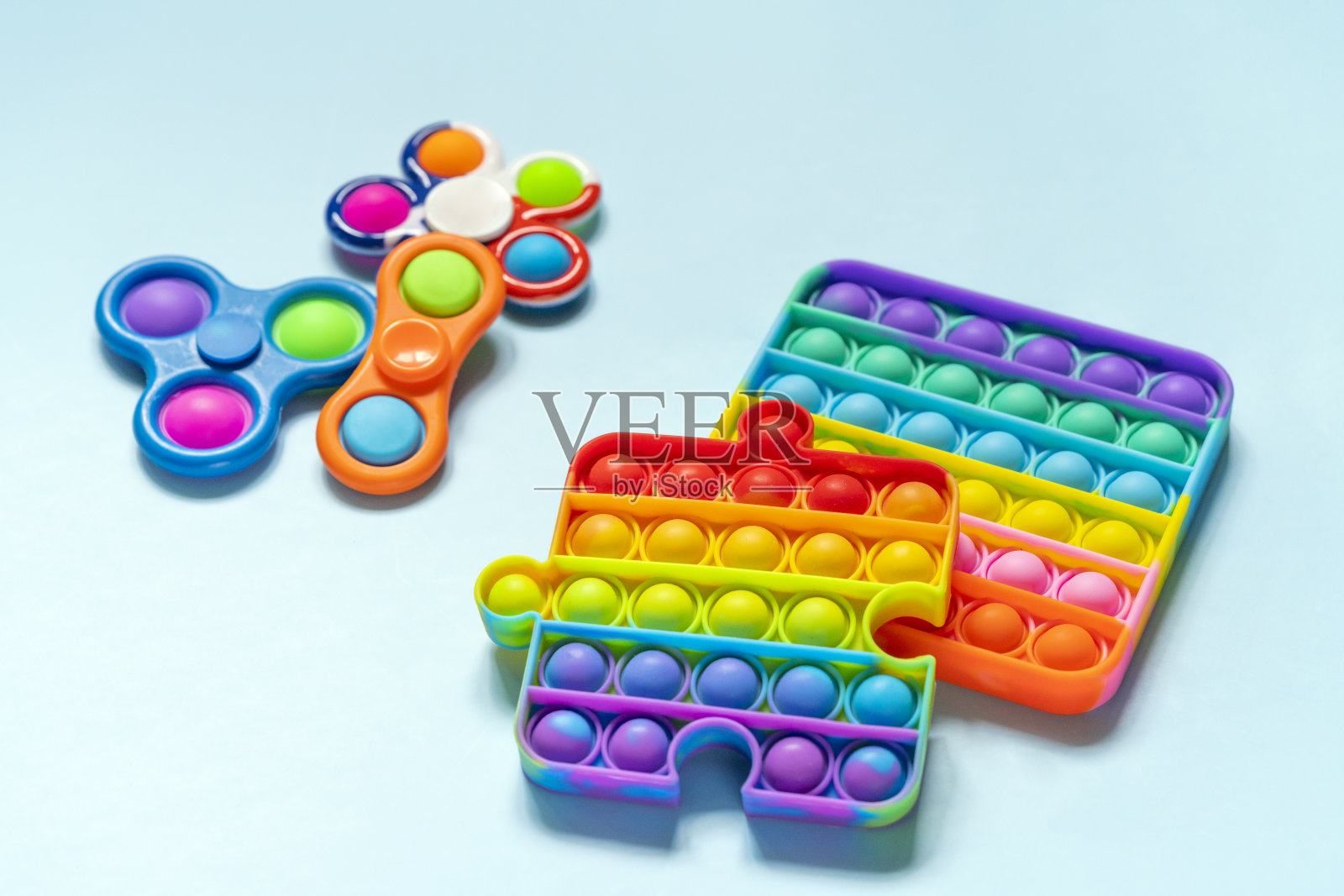 Pop it和Simple Dimple坐立不安玩具在蓝色的背景。彩虹反应力的玩具。游戏对孩子照片摄影图片