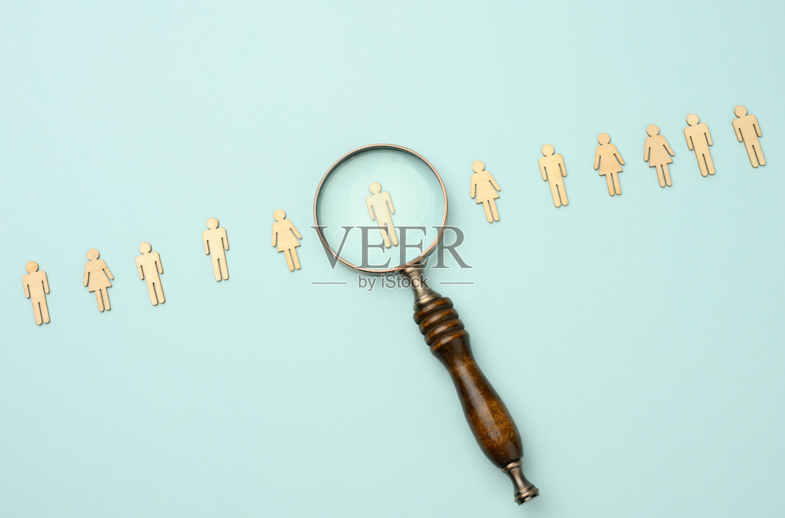 蓝色背景上的木头人和放大镜。招聘理念，寻找有才能的员工照片摄影图片