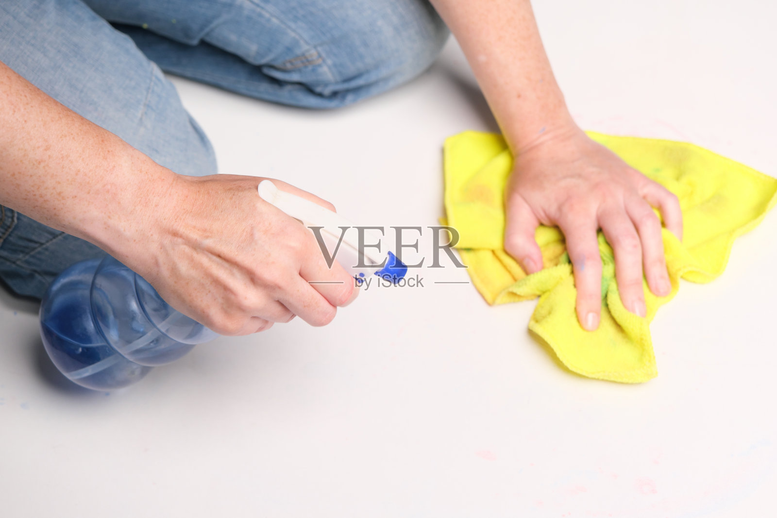 跪着的人正在用超细纤维抹布和清洁喷雾擦拭脏白色地板照片摄影图片