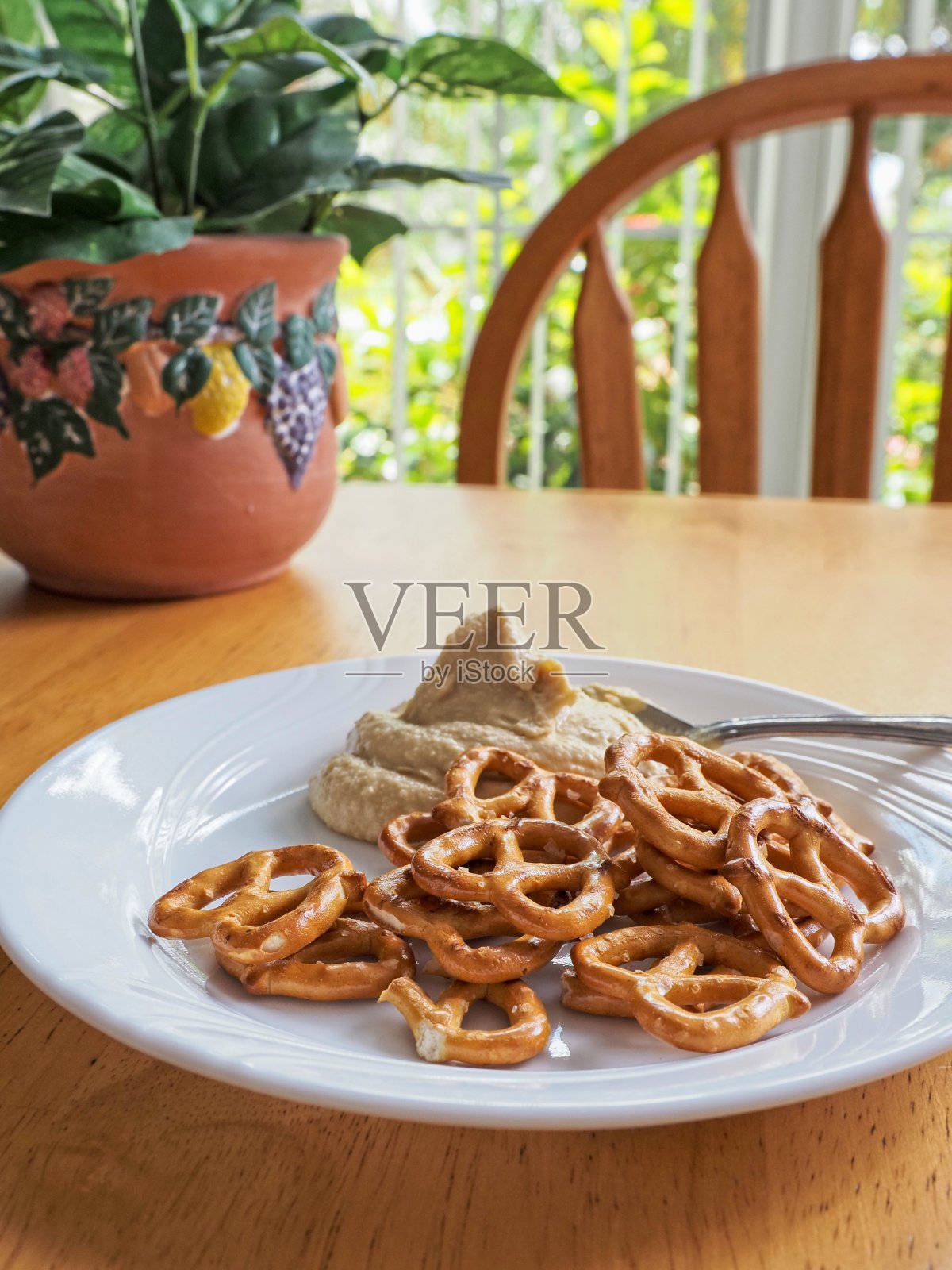 白色盘子上光滑的经典鹰嘴豆泥和心形扭扭椒盐卷饼照片摄影图片