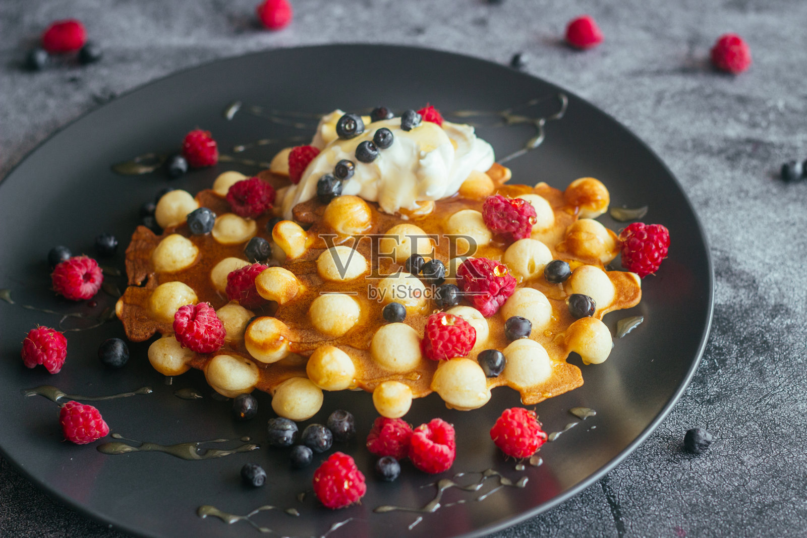 美味的香港华夫饼。华夫饼配覆盆子、蓝莓、酸奶油和蜂蜜照片摄影图片
