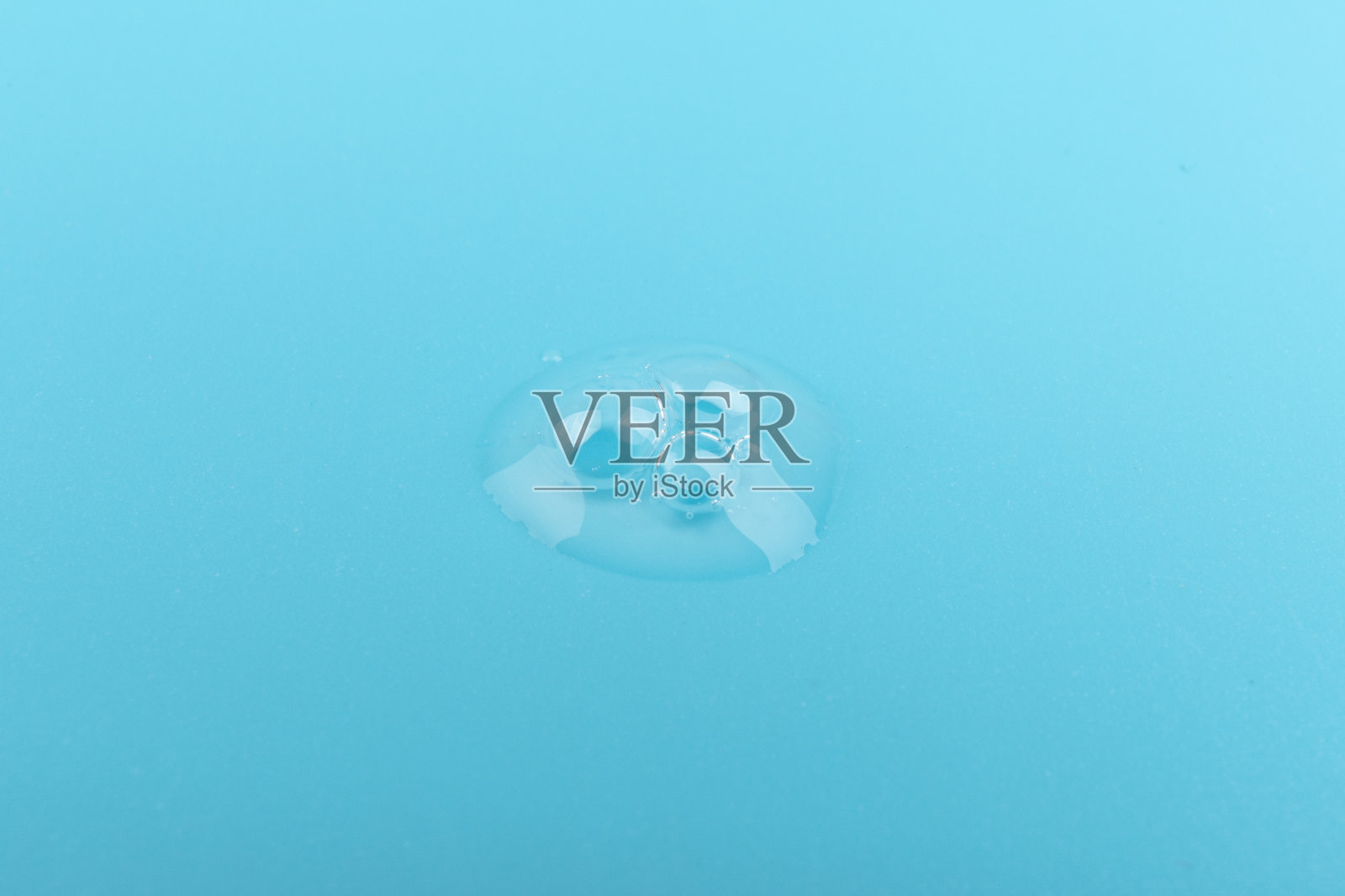 在蓝色背景下，脸部血清下降。照片摄影图片