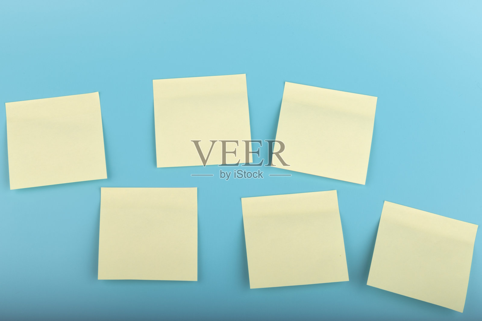 蓝色背景的黄色便利贴。方形粘纸提醒与阴影照片摄影图片