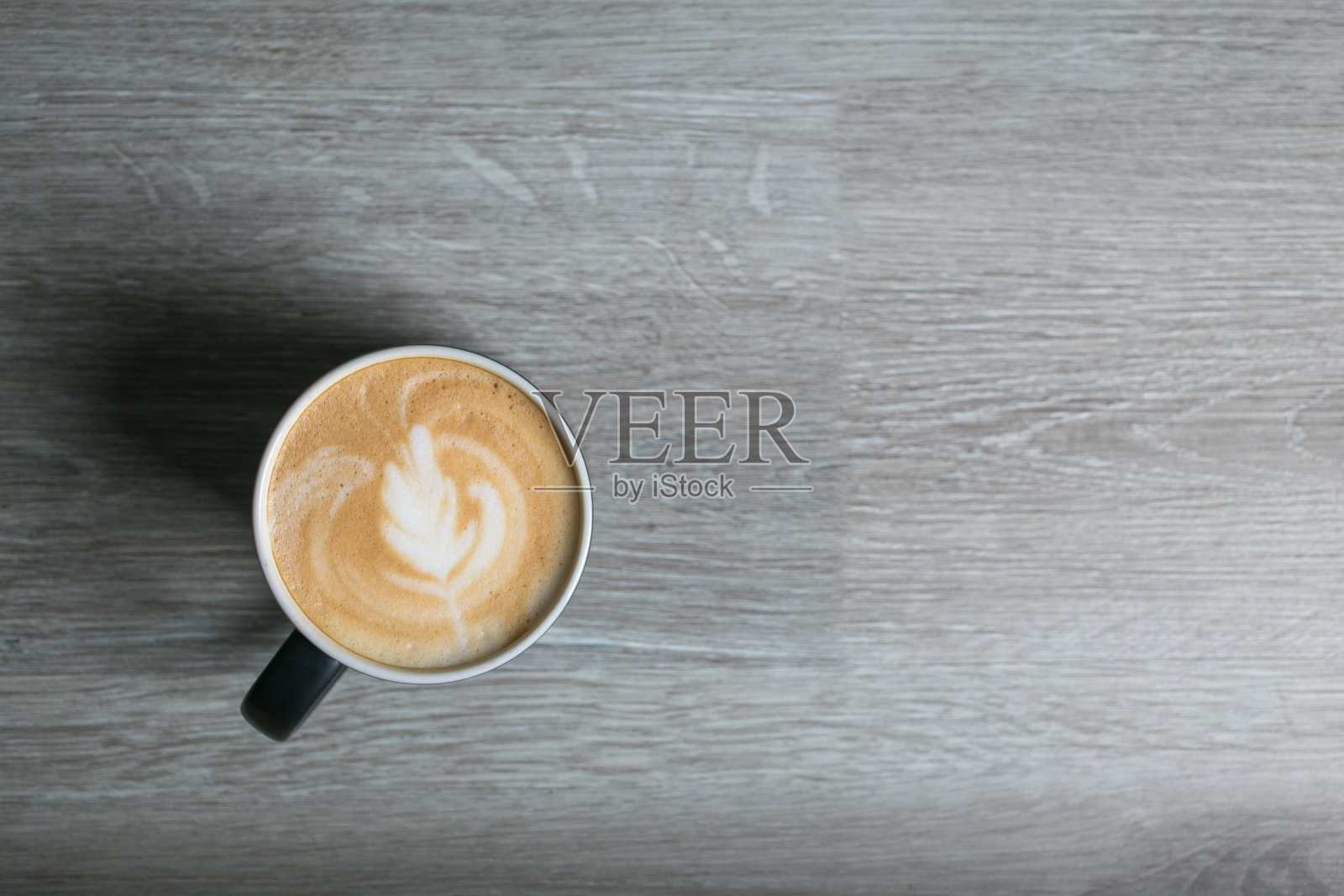 热咖啡杯的拉花艺术，咖啡在早上的木桌上。俯视图照片摄影图片