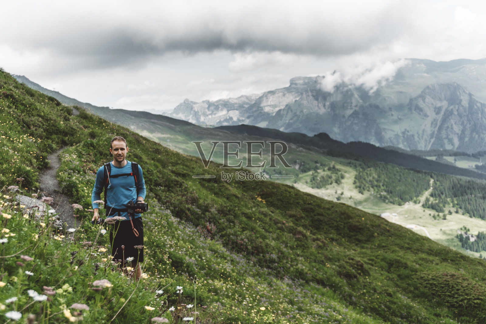 男性白种徒步旅行者看着摄像机，背景是群山照片摄影图片