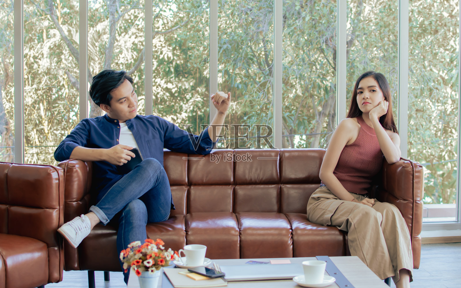 亚洲帅哥穿着休闲衬衫，和女友一起坐在客厅沙发上，在争吵后和解并向她伸出小指。情侣，爱情和生活方式的概念。照片摄影图片