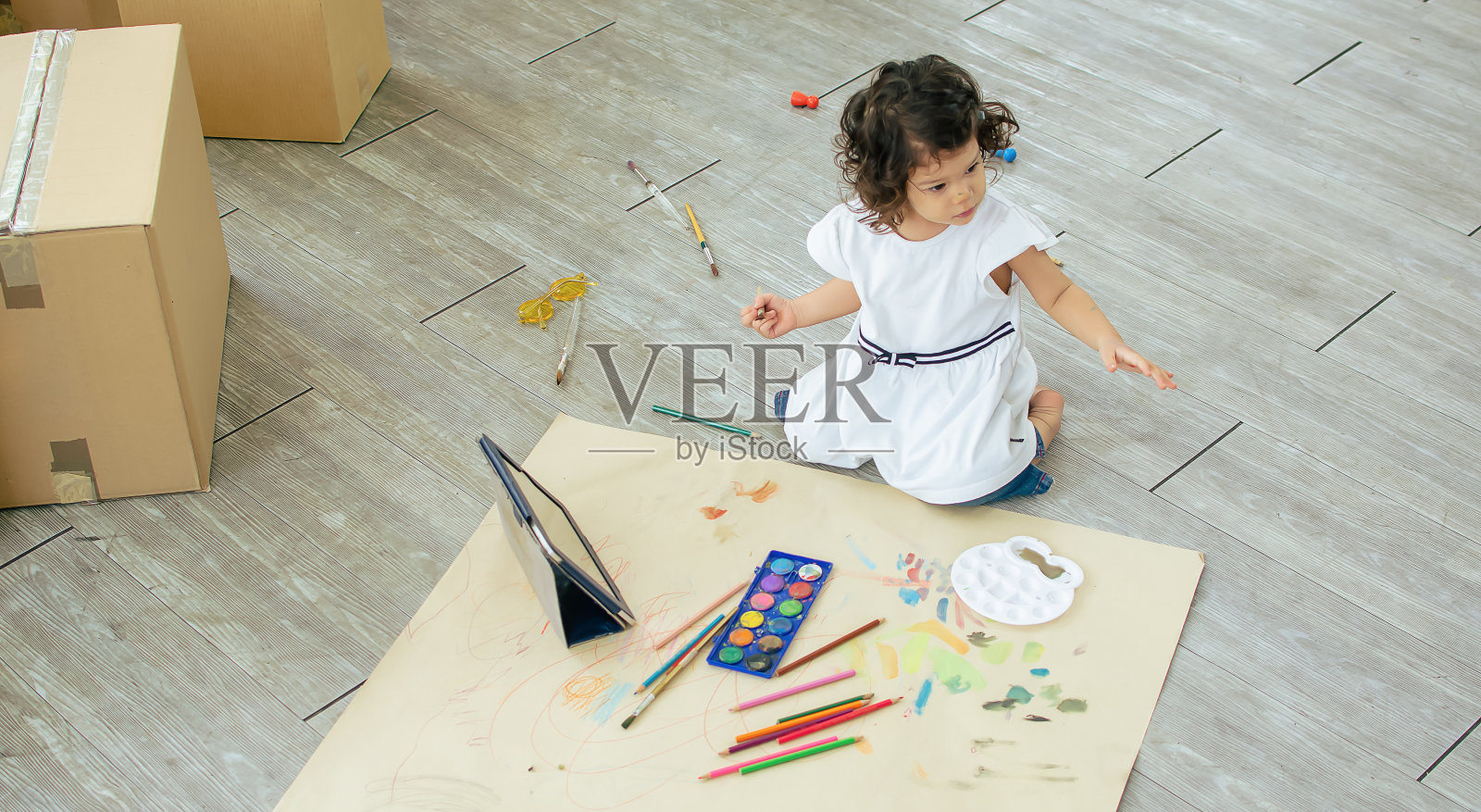 上面或鸟瞰图肖像小可爱可爱甜美的高加索卷发女孩开心地微笑着，玩得很开心，用彩笔在纸上画画，在家里的客厅里独自做活动。照片摄影图片