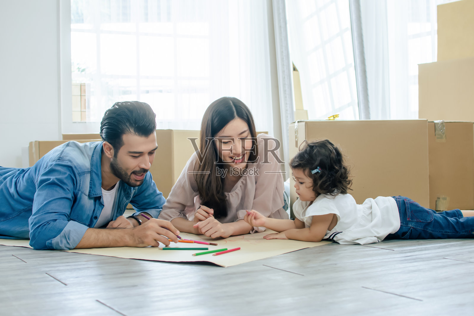 一个幸福的家庭，白种人英俊的父亲，亚洲人美丽的母亲和可爱的小女儿在家里做活动，一起玩，画画，画画作为假期的休闲和爱好。照片摄影图片