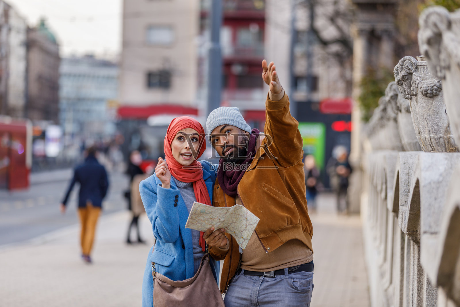 快乐的多民族夫妇走在街上，使用地图探索城市。照片摄影图片
