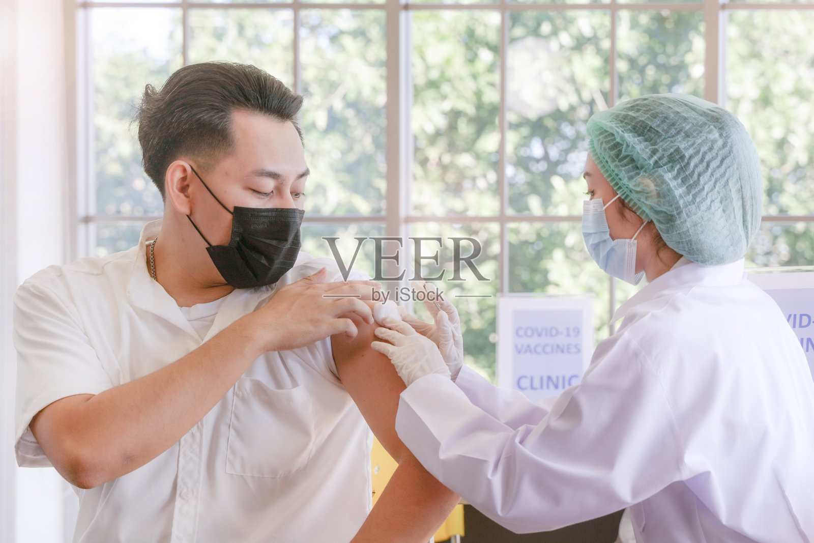 患者在诊所或医院接种新冠肺炎疫苗时，与护手一起注射疫苗，以获得免疫保护病毒。戴着防护口罩的青少年。照片摄影图片