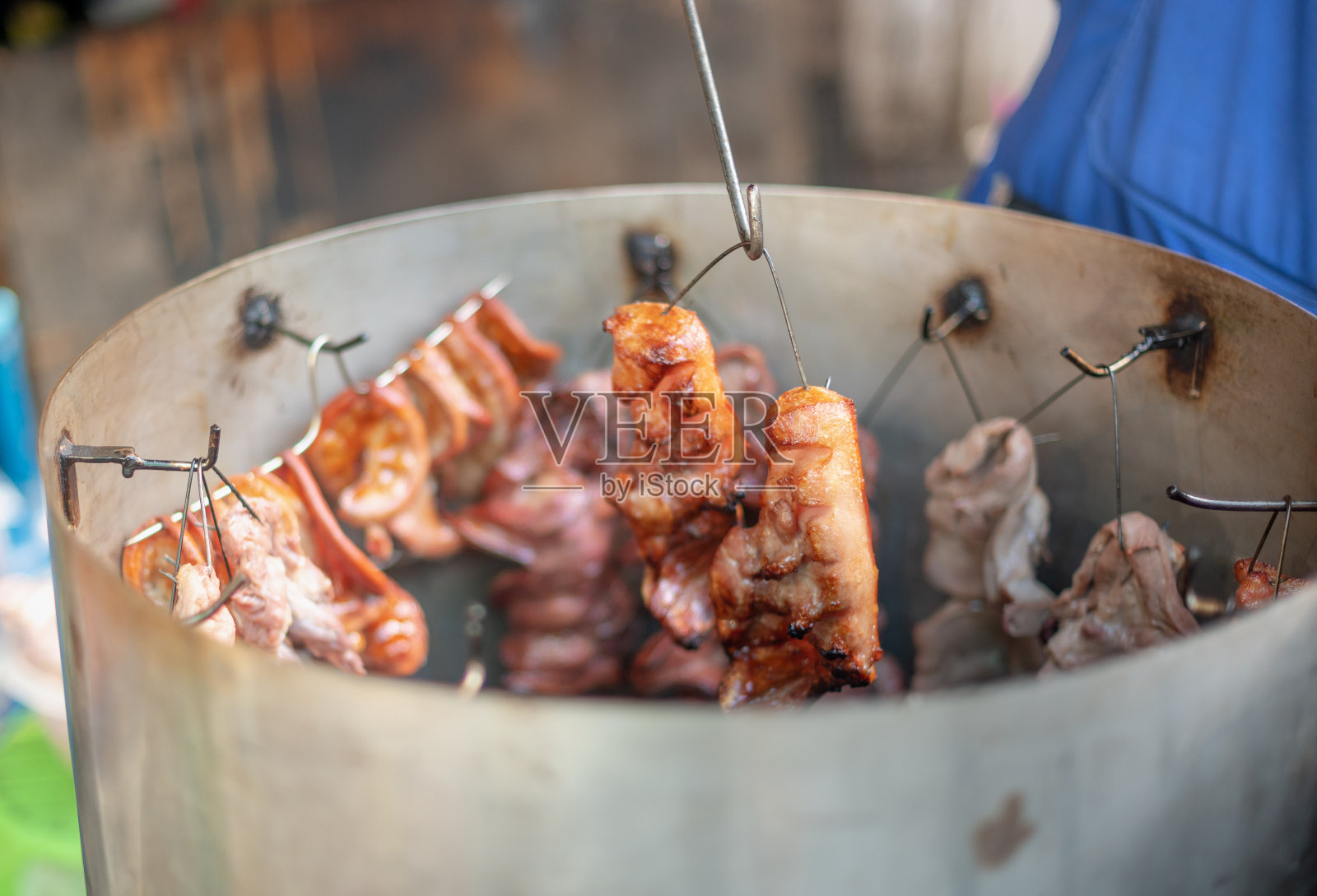 男手握钢肉和烧烤类腌制肉类在铝锅与木炭准备出售或服务给买家。照片摄影图片