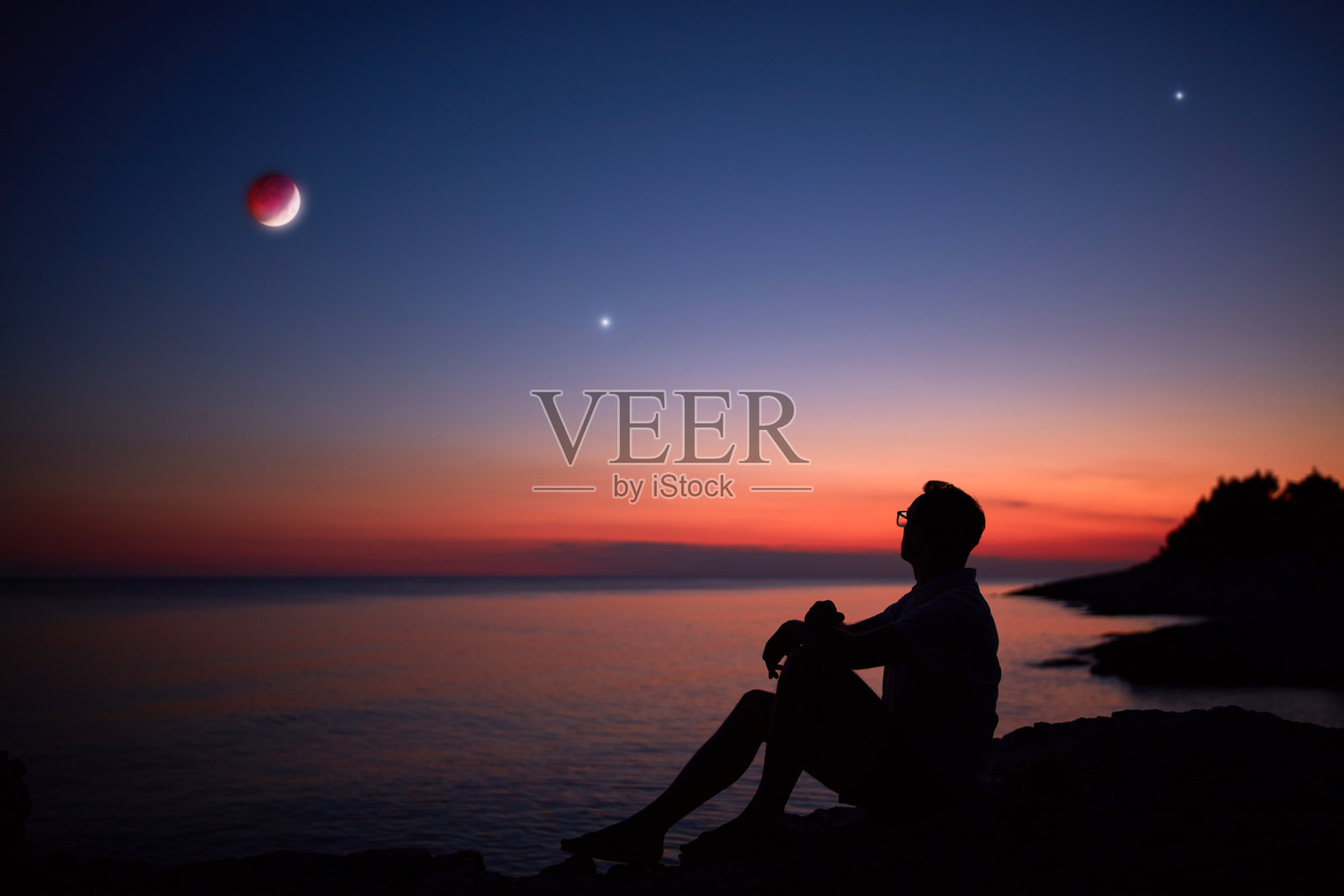 一个人的剪影看着月亮和星星在海上地平线。照片摄影图片