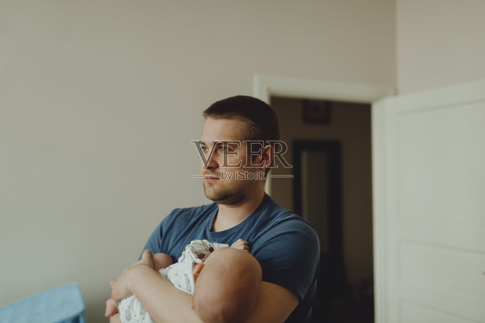 父亲怀里抱着熟睡的婴儿在公寓里转悠照片摄影图片