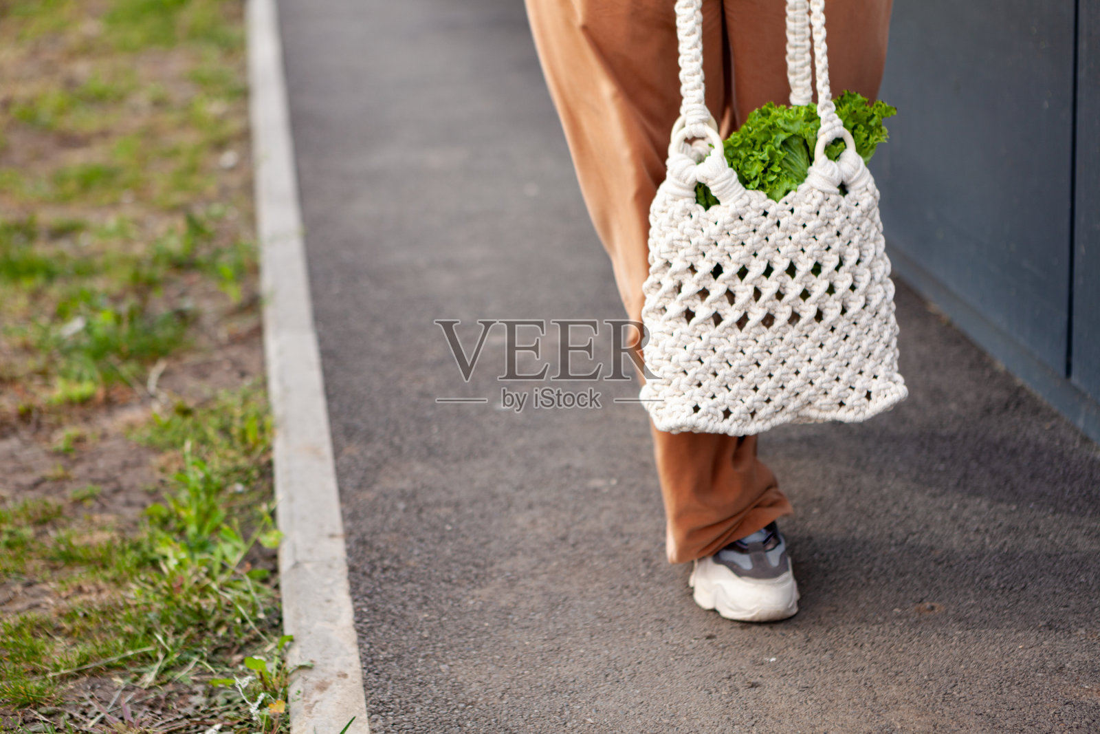 女孩正拿着装有蔬菜的网眼购物袋，绿色蔬菜没有塑料袋。零浪费，无塑料，环保理念。手工刺绣的袋子。可持续的生活方式。照片摄影图片