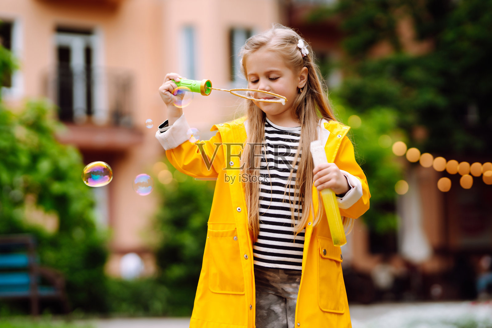 可爱的小女孩在夏日公园的户外吹肥皂泡。快乐的童年的概念。照片摄影图片