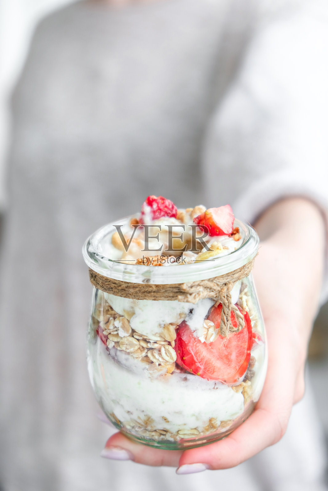 女手女吃健康早餐。燕麦格兰诺拉麦片，希腊酸奶，坚果，草莓麦片，在明亮的背景。健康。减肥饮食概念。排毒菜单照片摄影图片