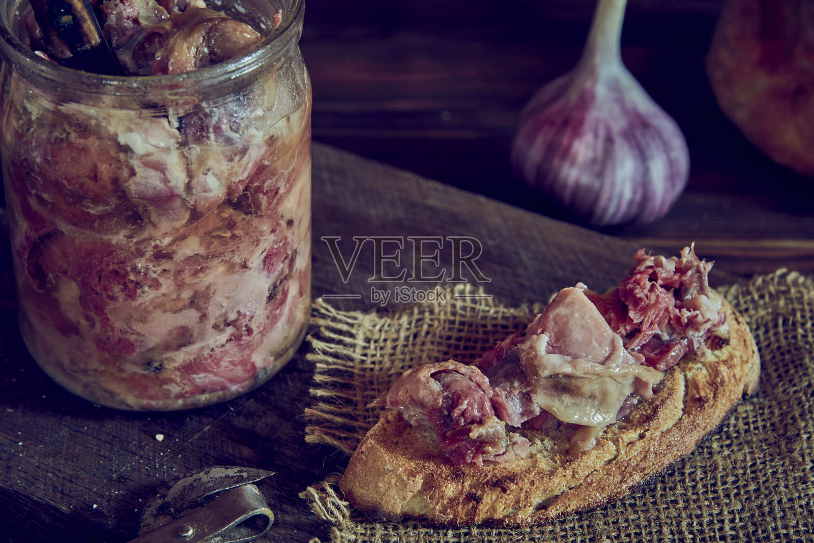一个装着自制炖菜的玻璃罐子和一个放在木砧板上的开胃三明治。照片摄影图片