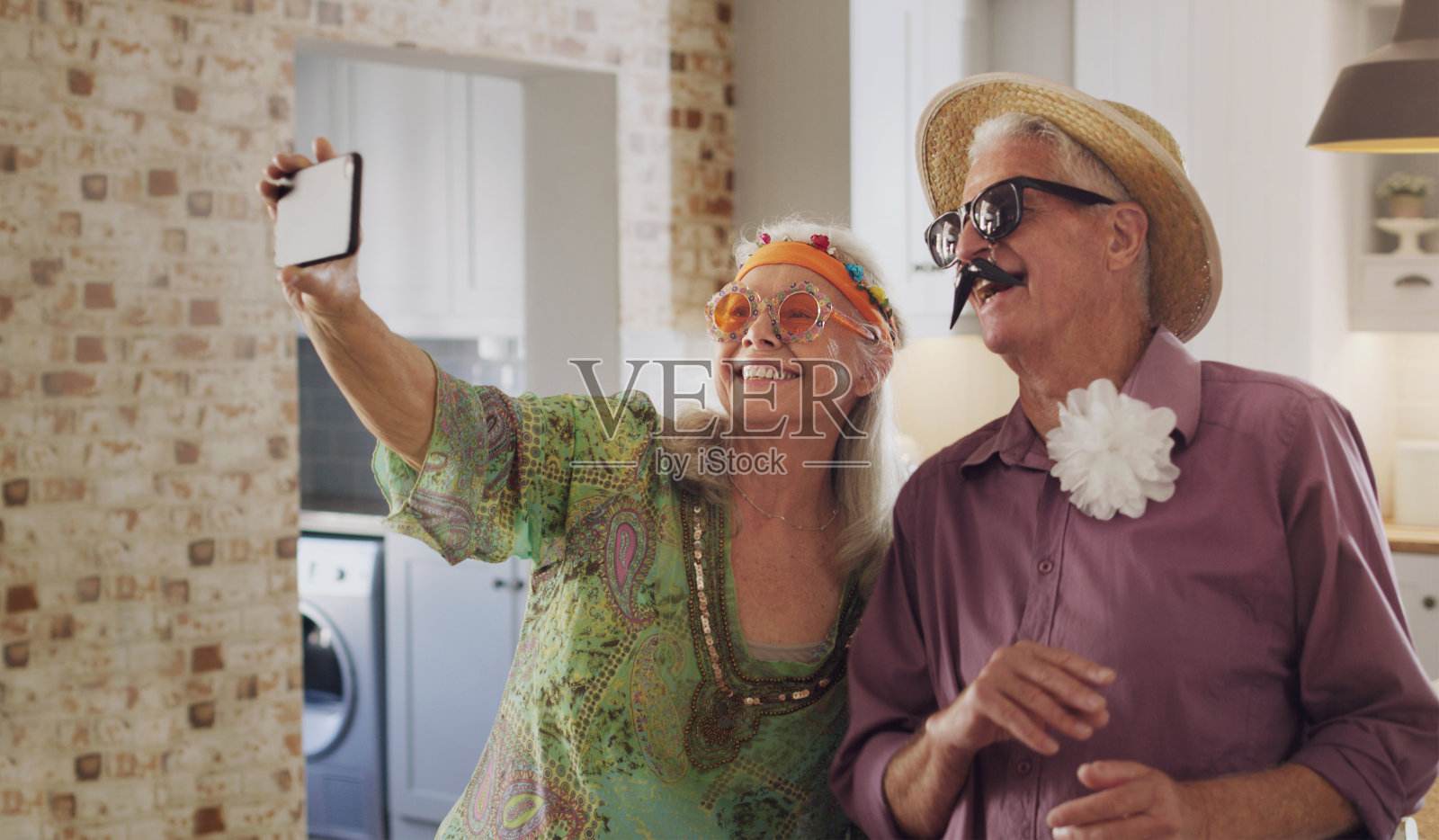 一对快乐的老年情侣穿着戏服站在一起，用手机自拍照片摄影图片