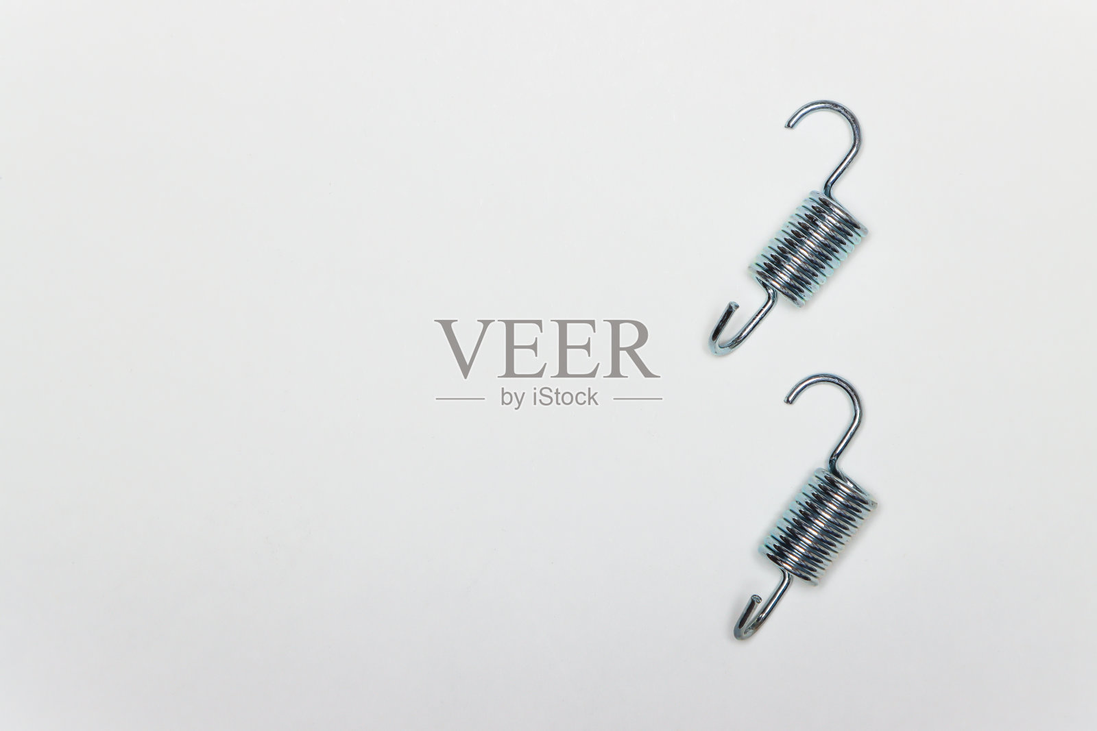 修理机器刹车用的两根短金属弹簧照片摄影图片