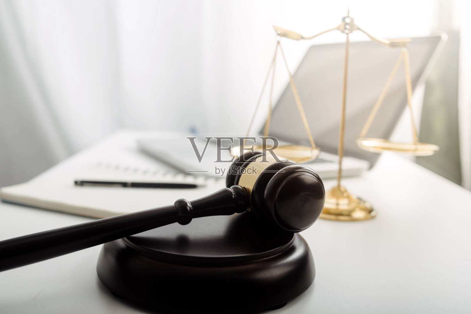 正义与法律观念。男法官在法庭上用木槌工作，电脑和对接键盘，眼镜，在晨光下放在桌子上照片摄影图片