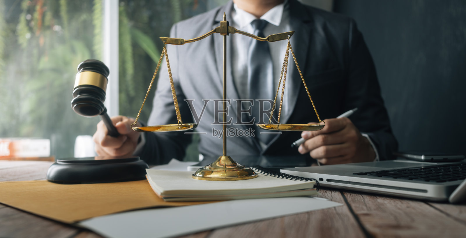 正义与法律观念。男法官在法庭上用木槌工作，电脑和对接键盘，眼镜，在晨光下放在桌子上照片摄影图片