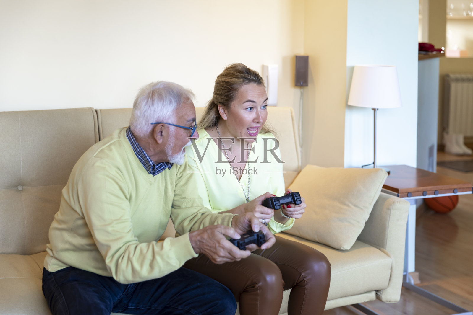 微笑的中年妇女和她的父亲一起在家里玩电子游戏。照片摄影图片