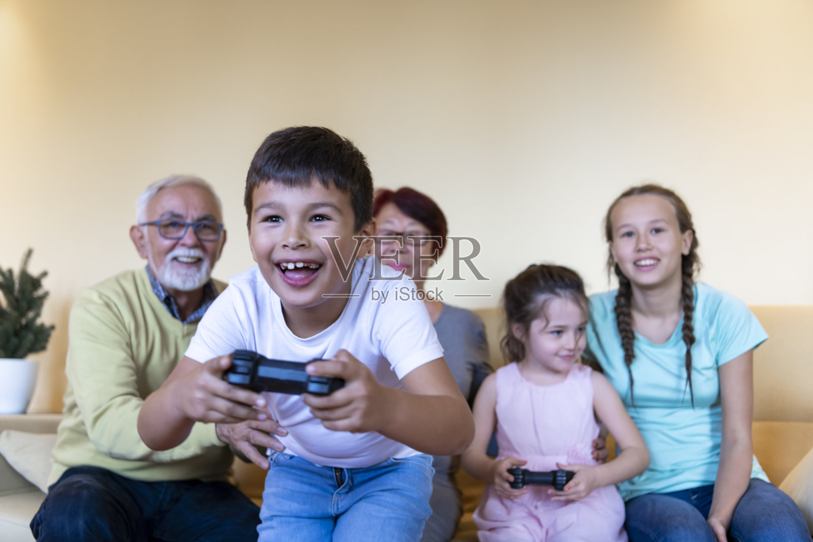 高兴的弟弟和妹妹在家里用操纵杆玩电子游戏。照片摄影图片