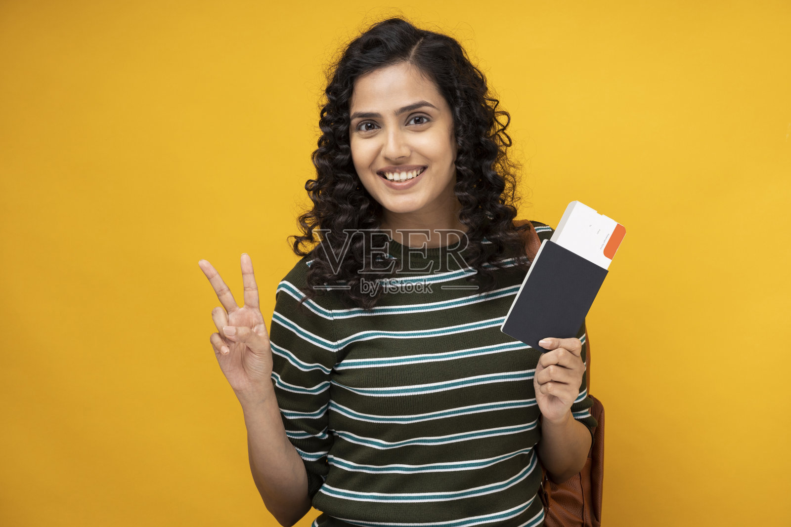 年轻女学生的肖像显示机票和护照站在黄色背景孤立照片摄影图片