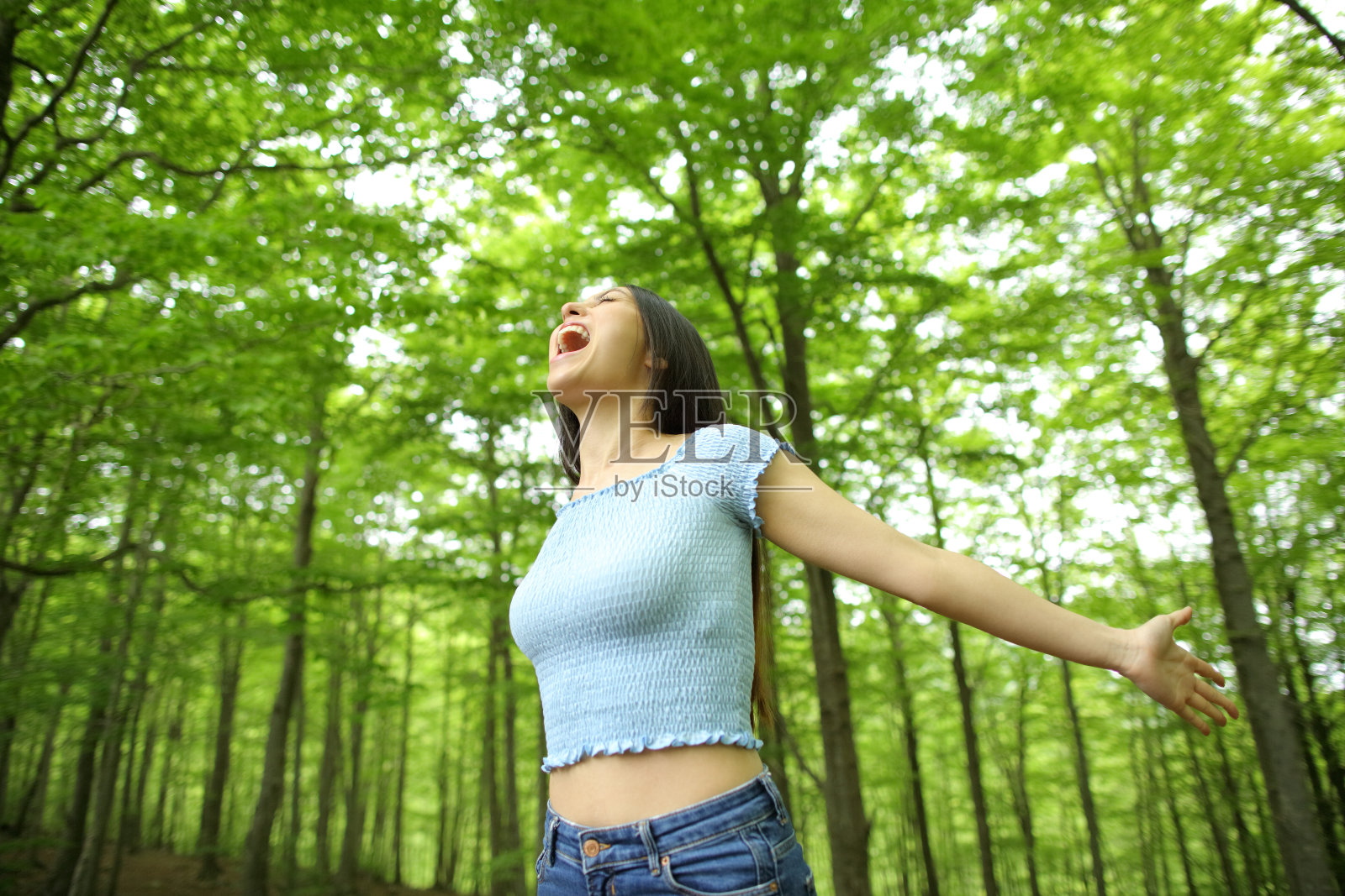 亚洲兴奋的妇女庆祝在绿色的森林照片摄影图片