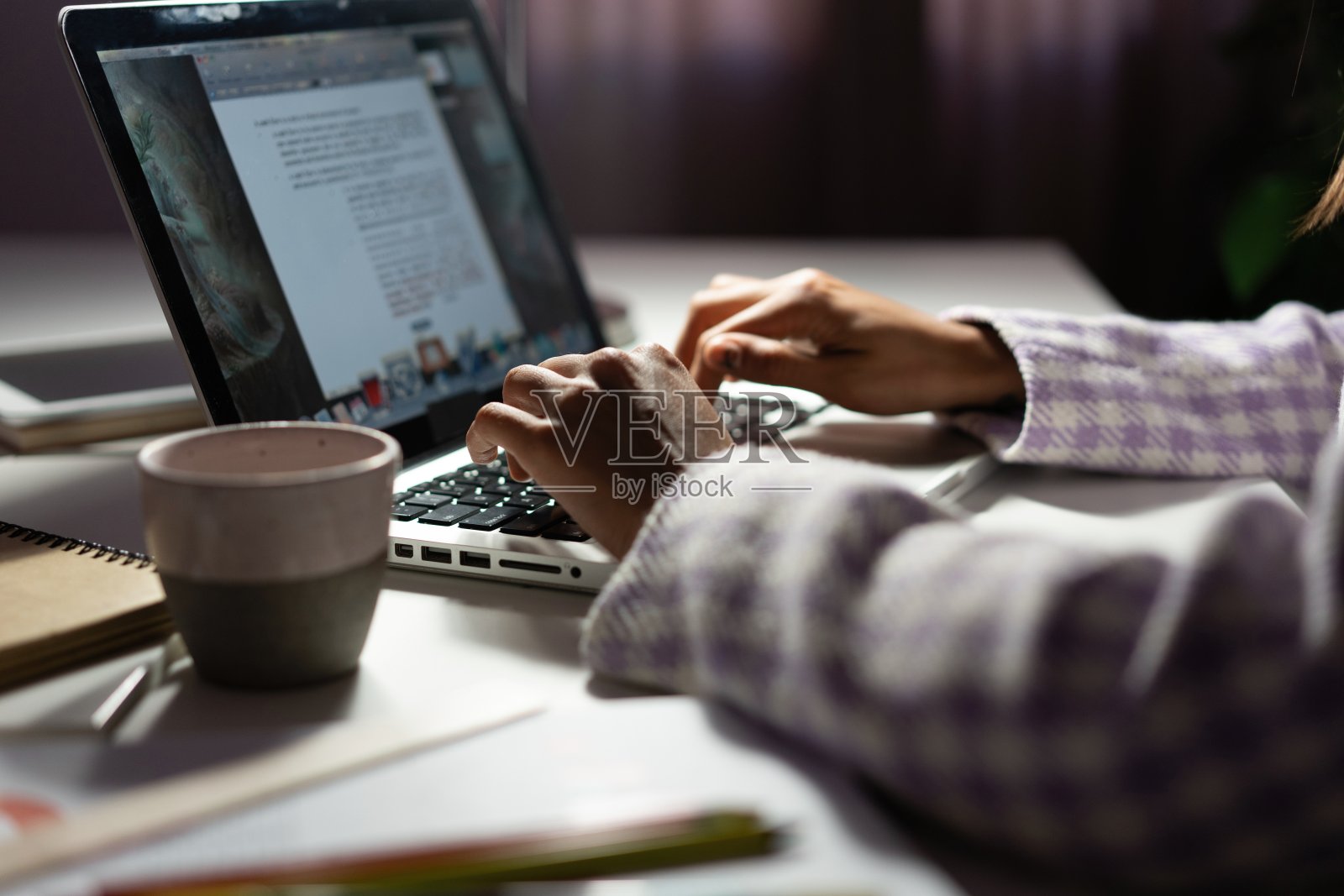 一位女士在深夜使用笔记本电脑处理一个新项目的想法。女性的手在笔记本电脑的键盘上打字照片摄影图片