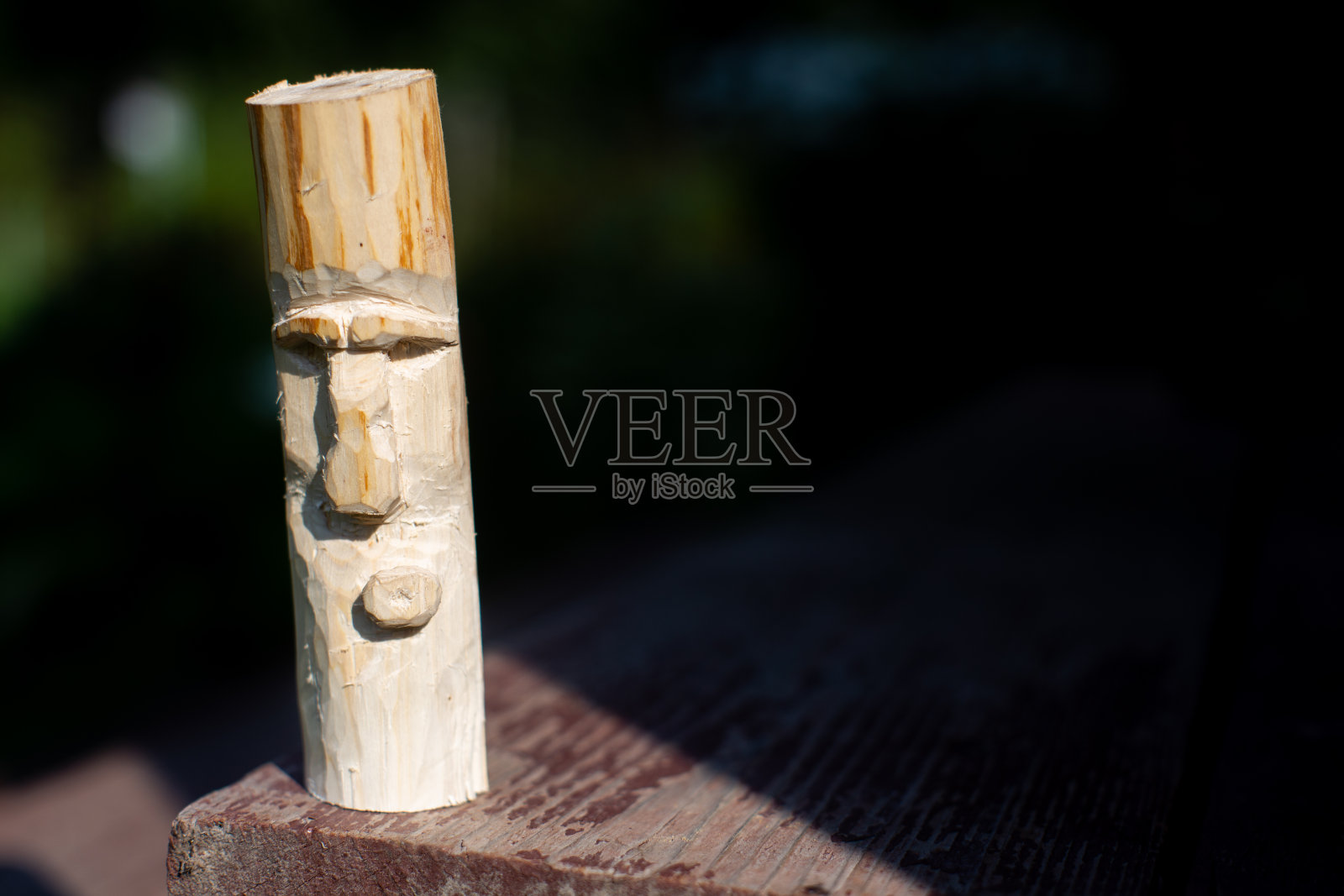 一块木板上立着一个木头雕刻的偶像。照片摄影图片