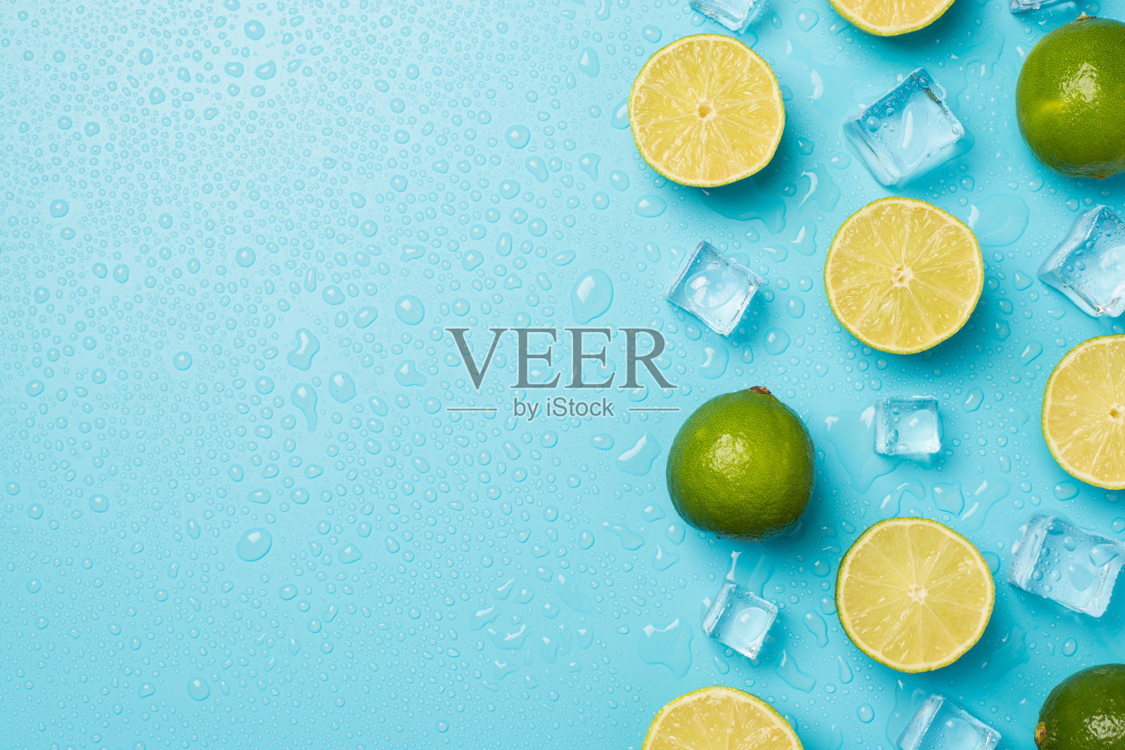 上面的照片是一堆酸橙，冰块和水滴孤立在蓝色的背景与空白照片摄影图片