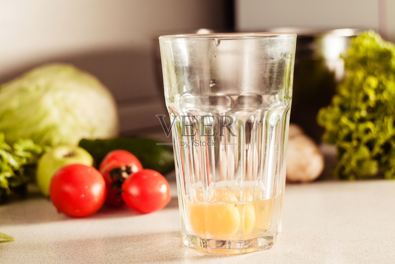 在厨房做煎蛋卷。在工作台上有一玻璃杯碎鸡蛋。蔬菜和香草摆放在附近照片摄影图片