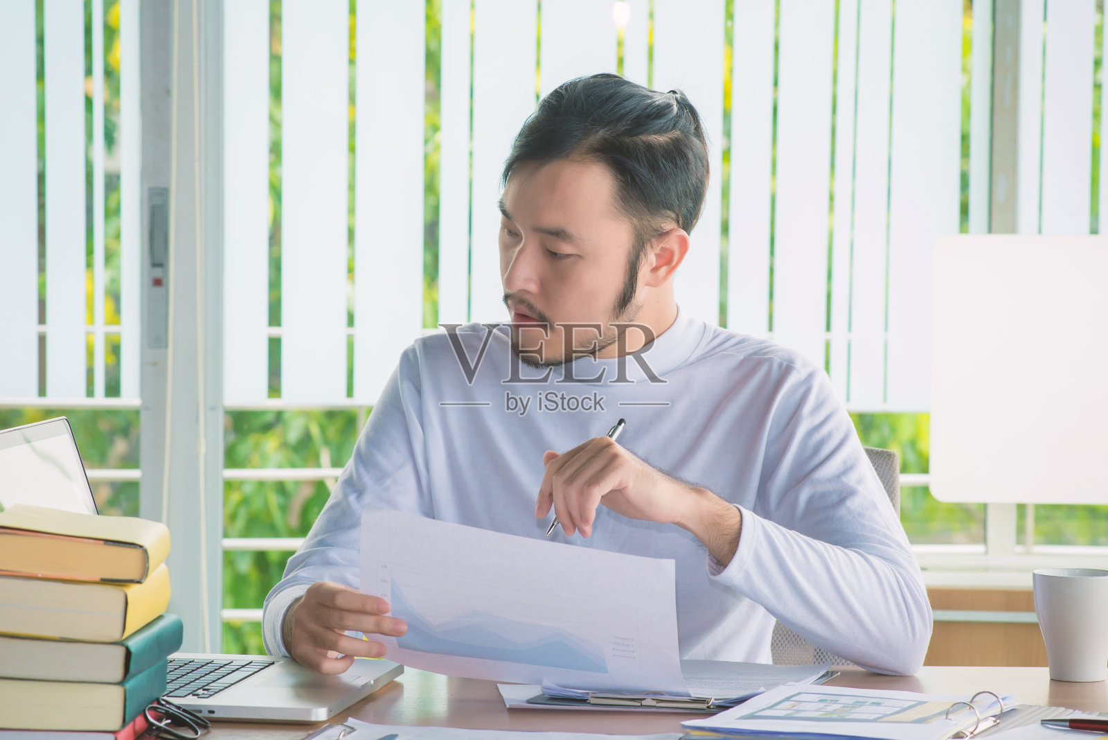 在办公室办公桌上使用笔记本电脑和文件的商务人士照片摄影图片