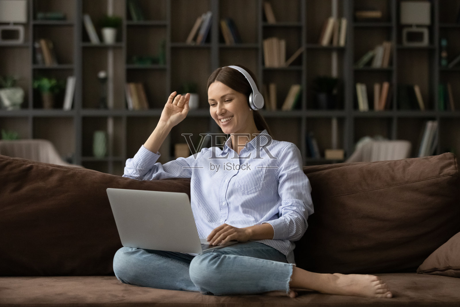 快乐的年轻女子戴着耳机进行电脑视频通话。照片摄影图片