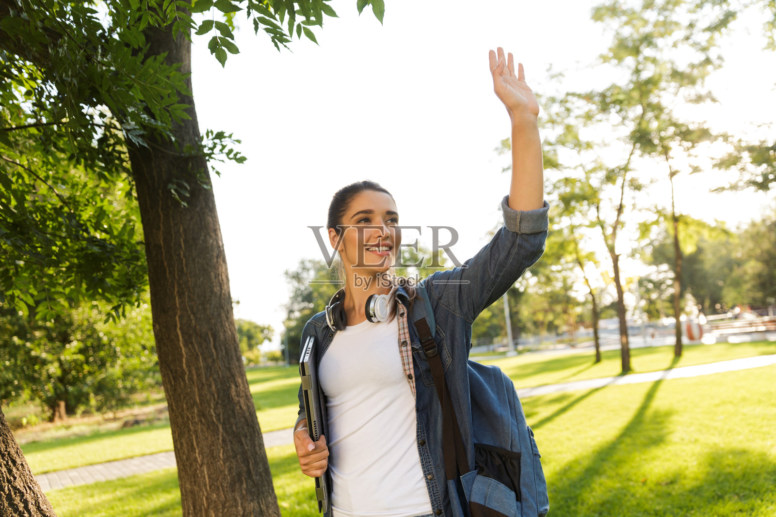 漂亮的女学生拿着笔记本电脑在公园里散步照片摄影图片