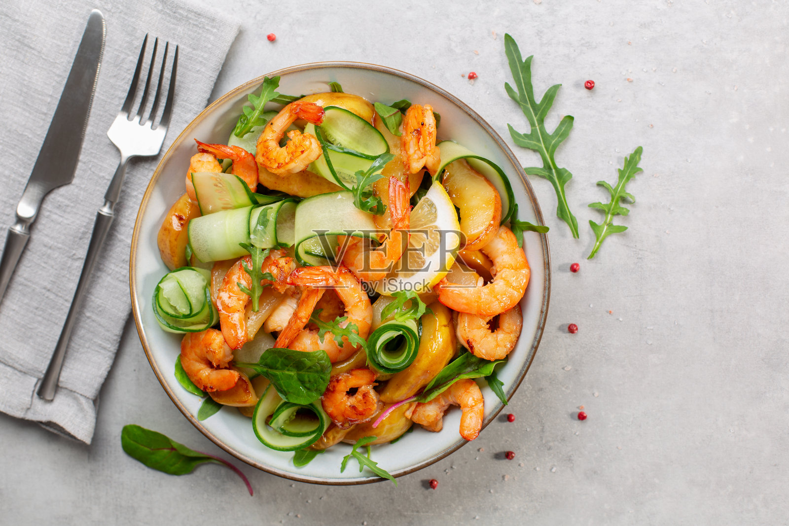 新鲜沙拉配烤大虾，焦糖梨，黄瓜和混合蔬菜，柠檬汁。浅灰色的背景。直接上图。副本的空间。照片摄影图片