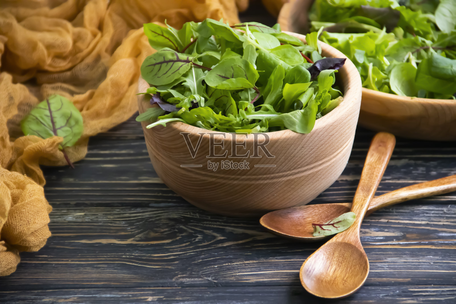 绿色的沙拉叶子在一个盘子里，在一个木制的背景照片摄影图片