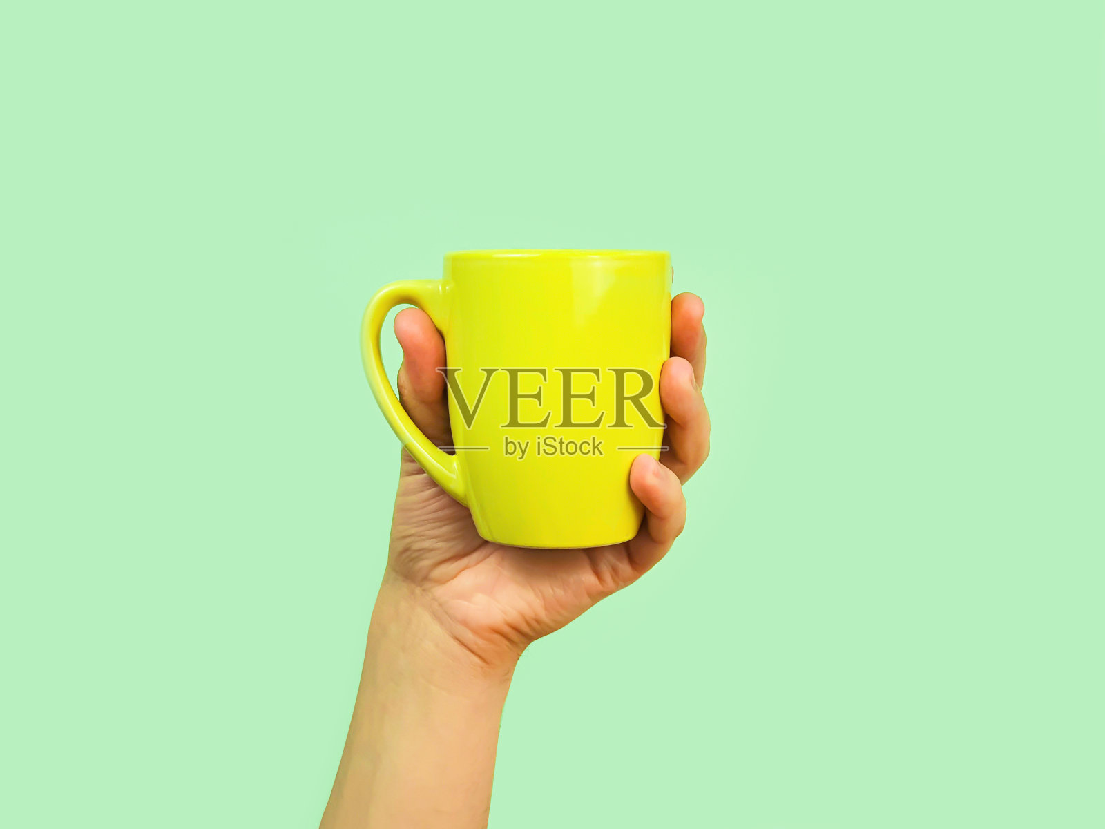 男手捧绿杯，绿色背景上。模型,前视图照片摄影图片