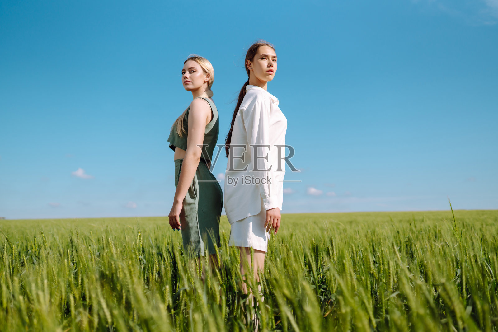 两个金发女孩的肖像穿着时髦的衣服，背景是一个田野。照片摄影图片