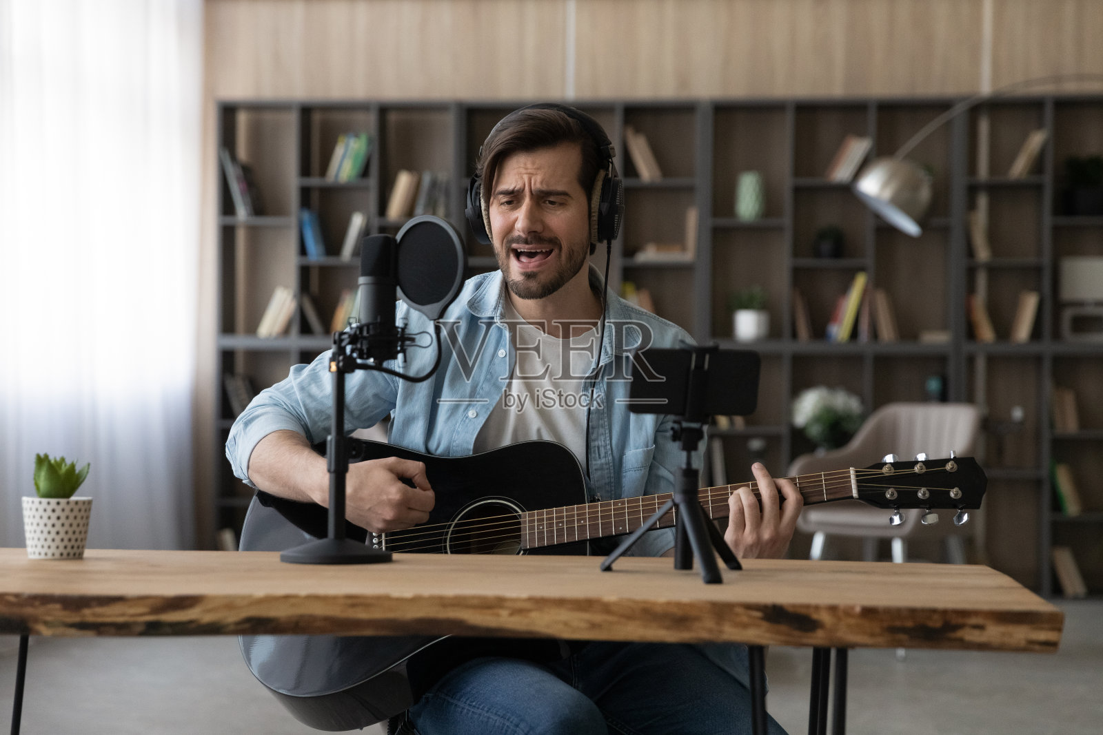 快乐年轻的灵感男子弹吉他，录制自己的歌曲。照片摄影图片