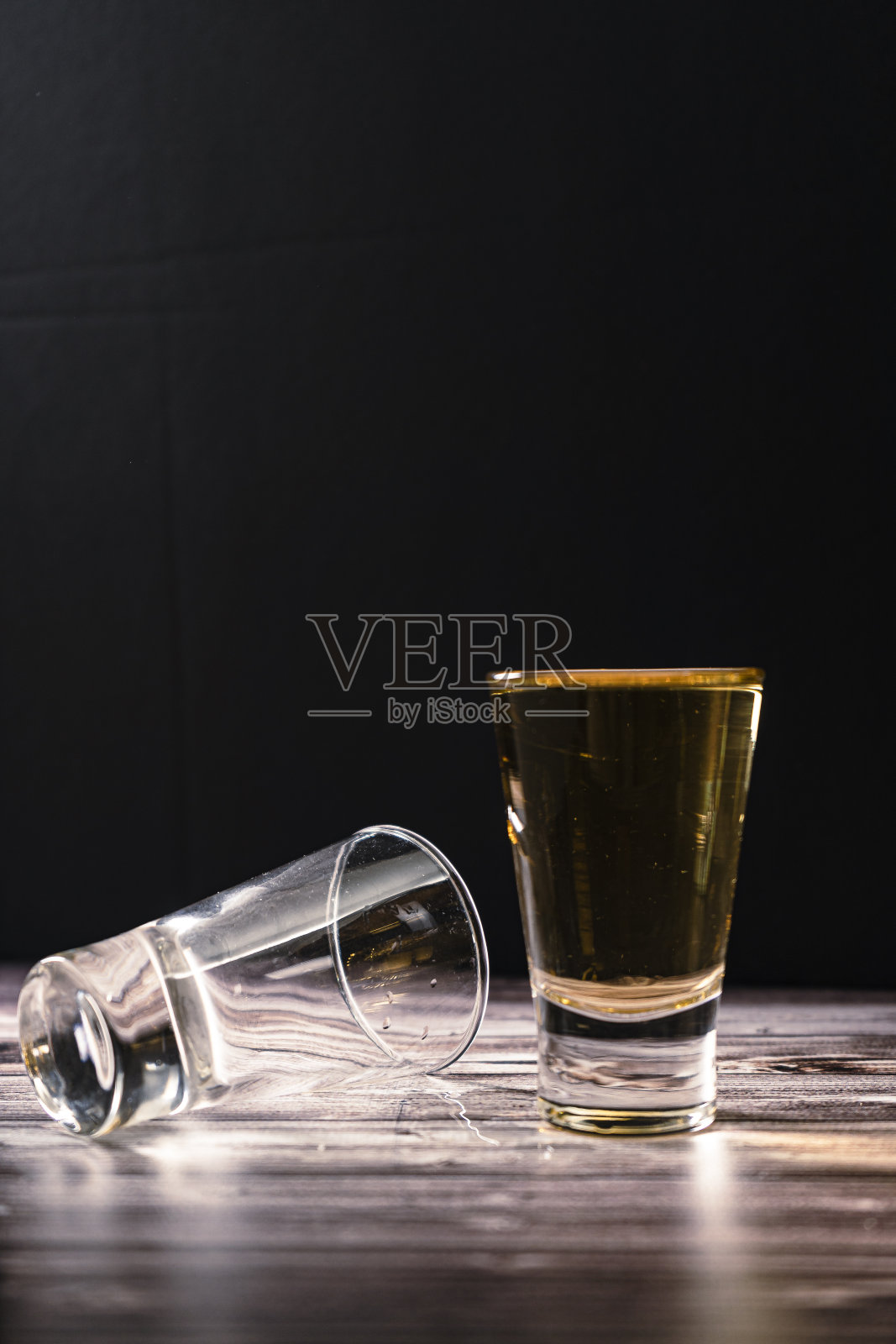 将一杯威士忌、苏格兰威士忌或波旁威士忌放在第二杯旁的垂直视角。照片摄影图片