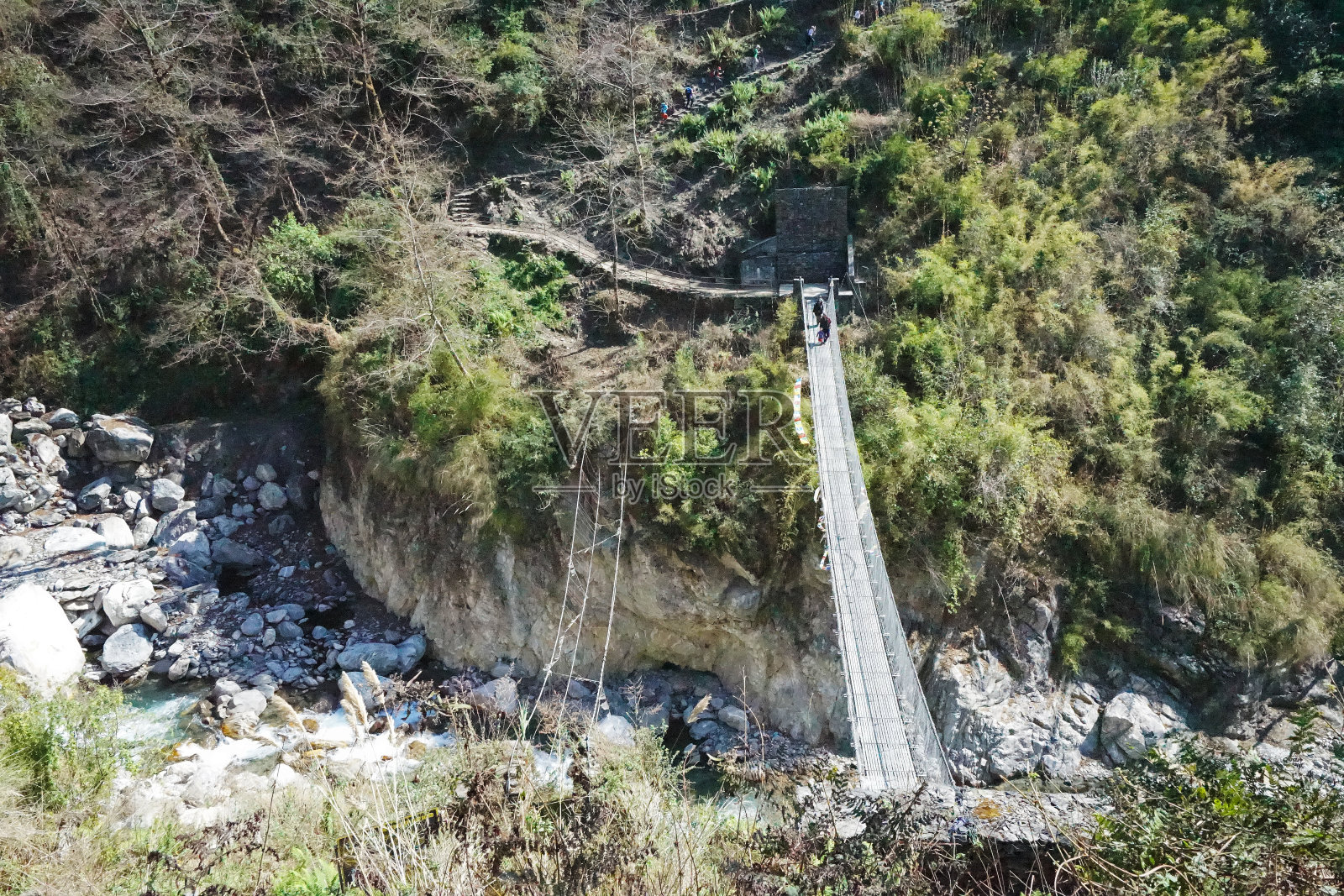 吊桥横跨尼泊尔村的天然石溪——尼泊尔照片摄影图片