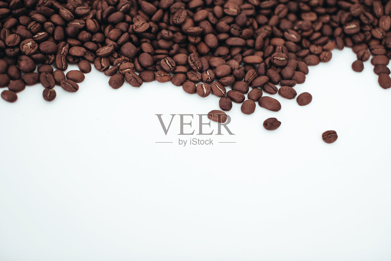 在白色背景下分离出的芳香的深棕色咖啡豆。照片摄影图片