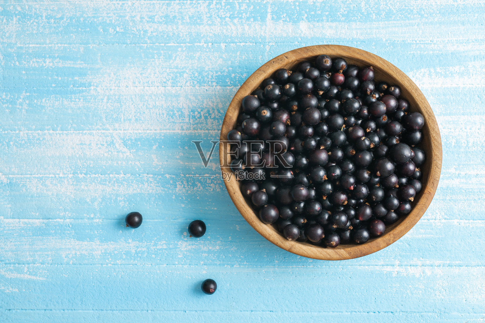 黑色的桌子上，木碗里的新鲜黑加仑子照片摄影图片