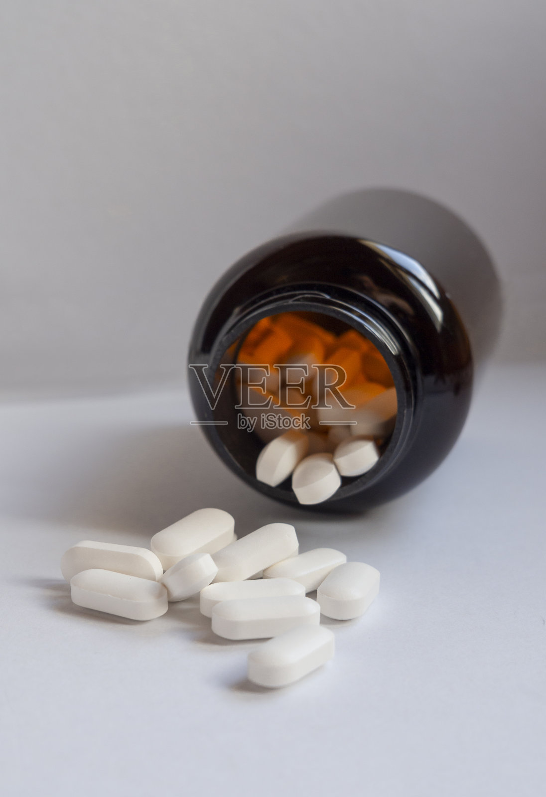 棕色瓶子中散落的白色药丸照片摄影图片