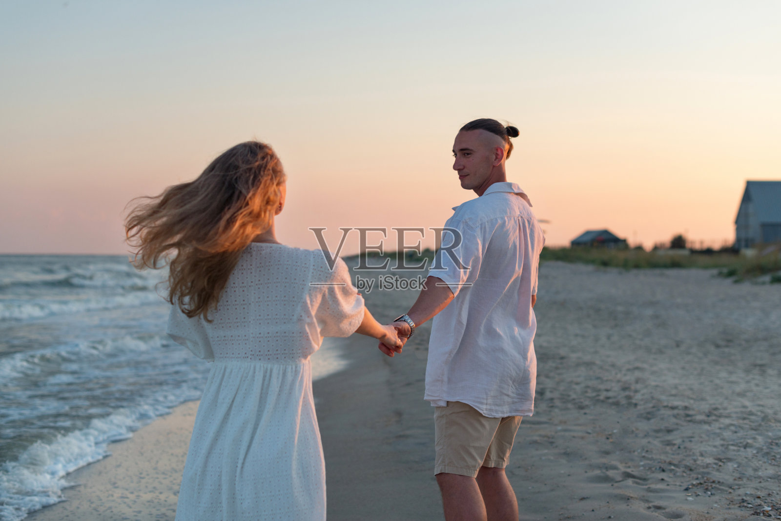 幸福的情侣在日落时分的海边漫步照片摄影图片