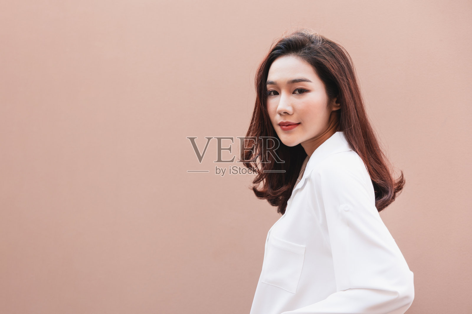 年轻的亚洲女人摆出时髦的样子。肖像一个微笑的黑发女人自然化妆穿时装衣服。漂亮的女模特穿着一件白色的大衬衫。人美丽的概念。照片摄影图片