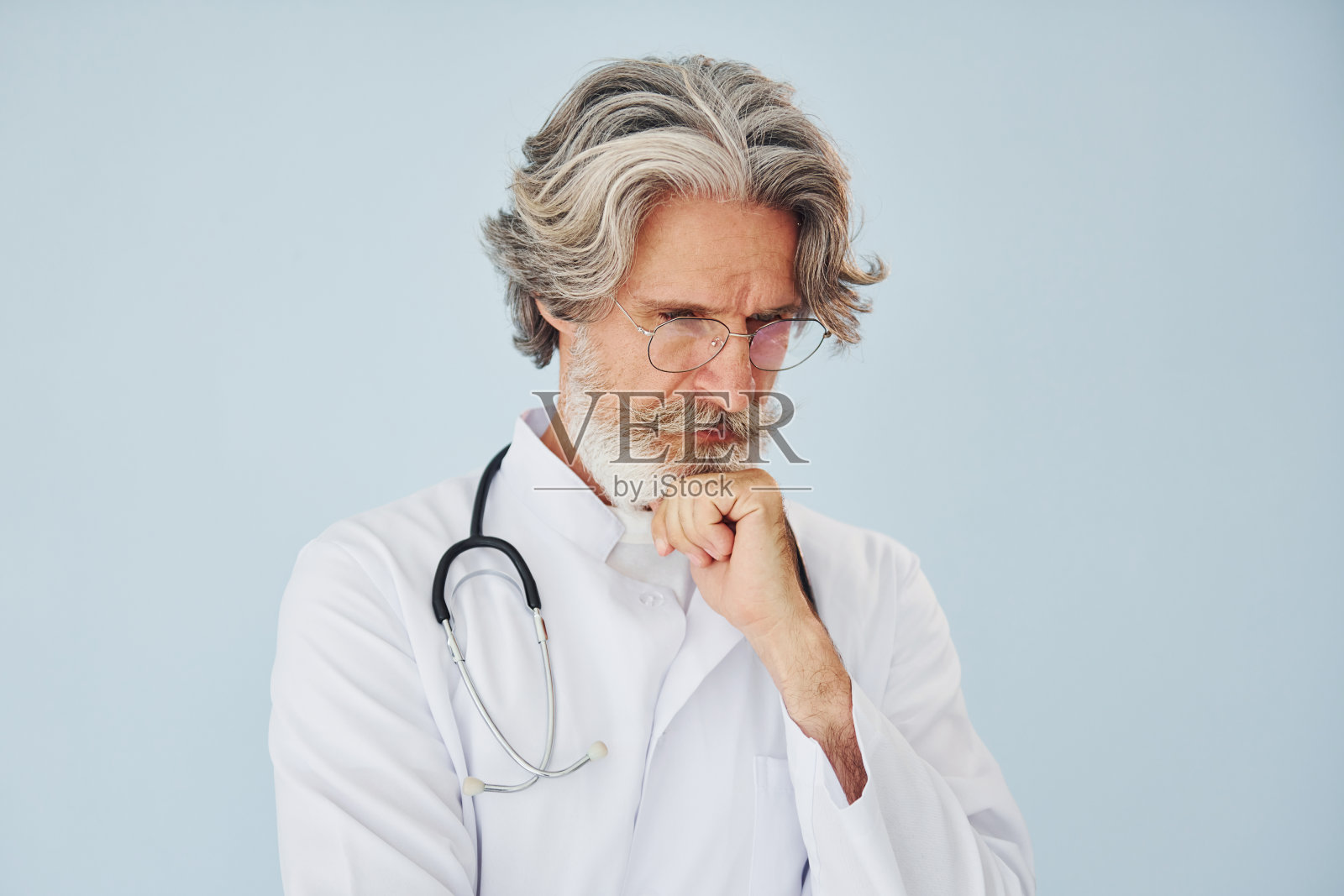 穿白大褂的医生靠在墙上。室内有灰色头发和胡子的高级时尚现代男士照片摄影图片